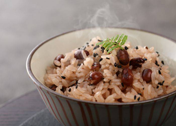 A steaming bowl of red bean rice, featuring adzuki on top of rice.